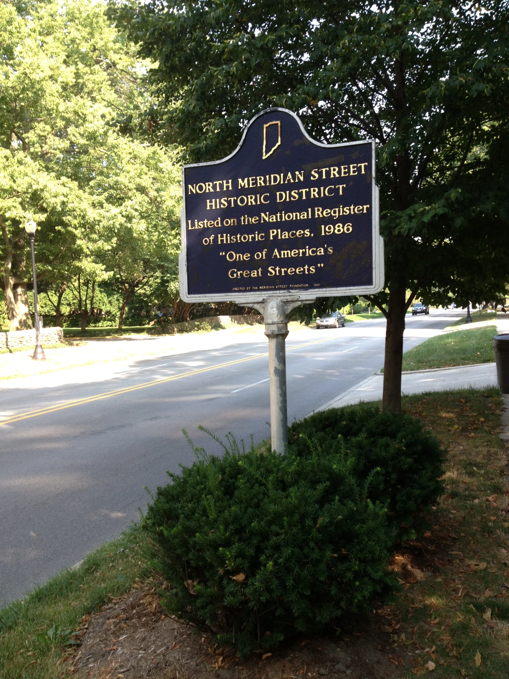 a blue plaque with writing on it near trees