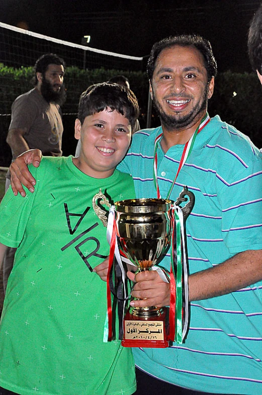 two people are holding up a trophy and posing for the camera