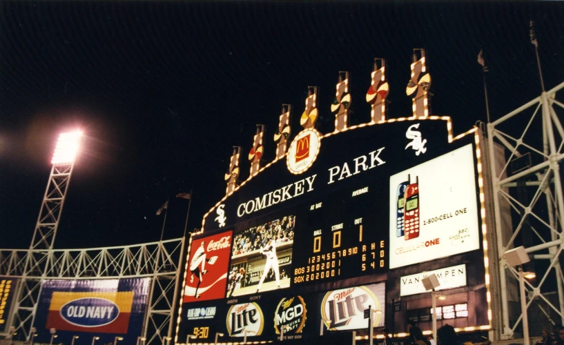 a baseball stadium with large signs lit up at night