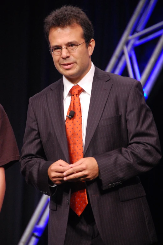 a man wearing a suit and tie stands in front of some stage lights