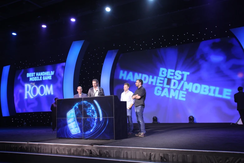 four people stand on stage during a game show