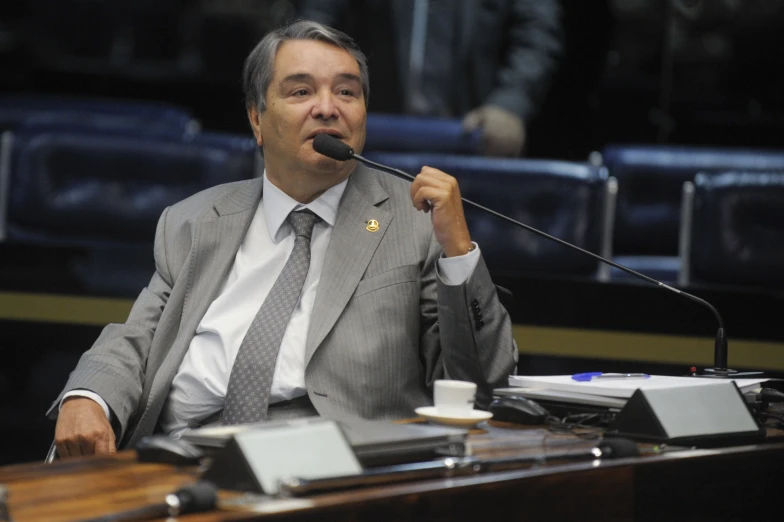 a man sitting at a table speaking into a microphone