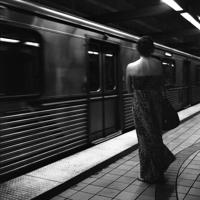 a woman in a long dress walking out of a subway