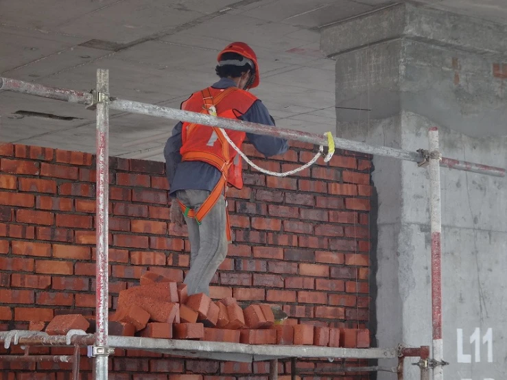 a bricklayer using a drill hammer to install a wall