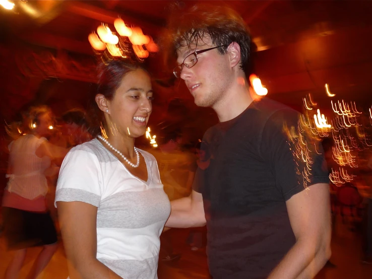 a man and woman dancing a night at an open air event