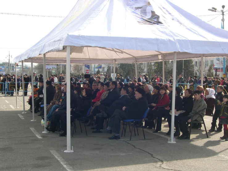 there are people sitting under a large canopy at a gathering