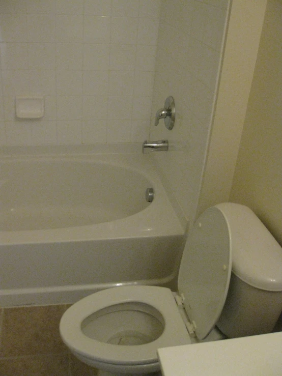 a white bathroom with toilet and tub next to it