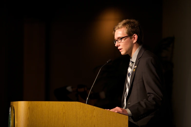 a man wearing glasses stands at a podium