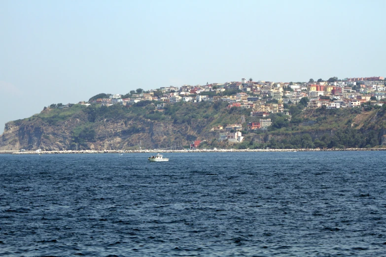 small boat in open water with a city on top of a hill