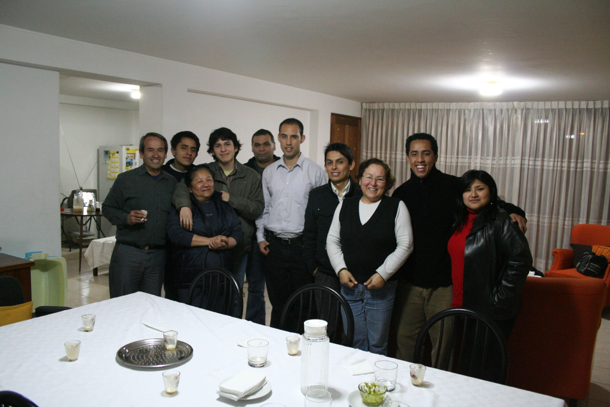 the group of people is standing together in front of the table