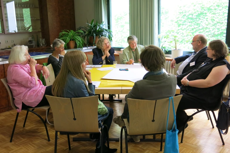 group of older people sitting around a wooden table