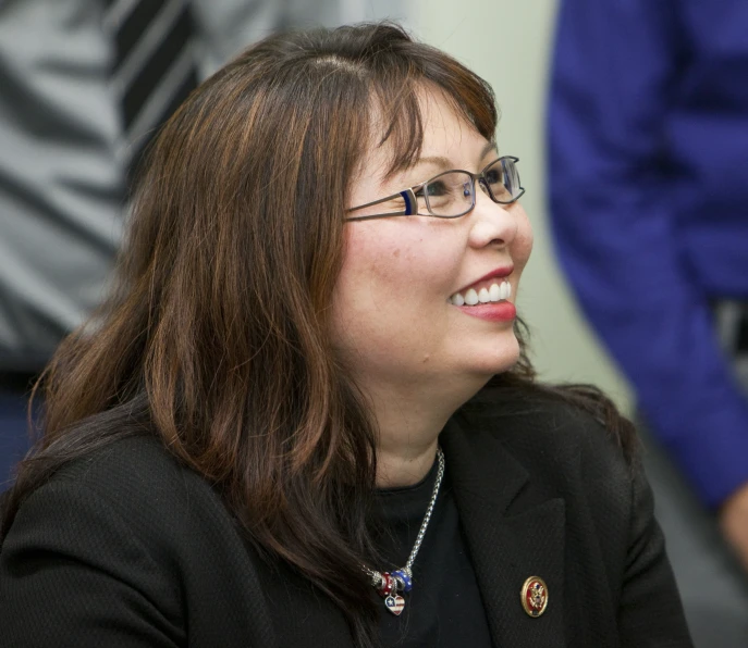 an asian woman wearing glasses and looking at soing