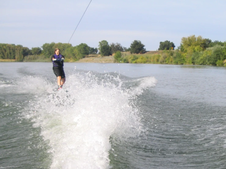 water skier in wet suit on lake with trees