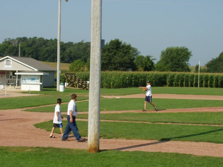 an adult and two children playing baseball on a field