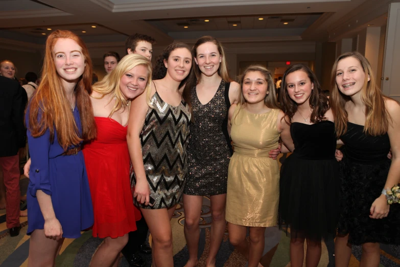 several young women dressed in dresses stand together