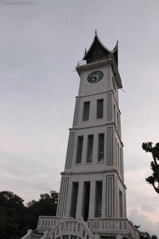 a tall white clock tower sitting above a park