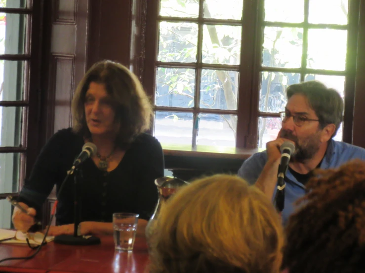 three people sit at tables talking into microphones