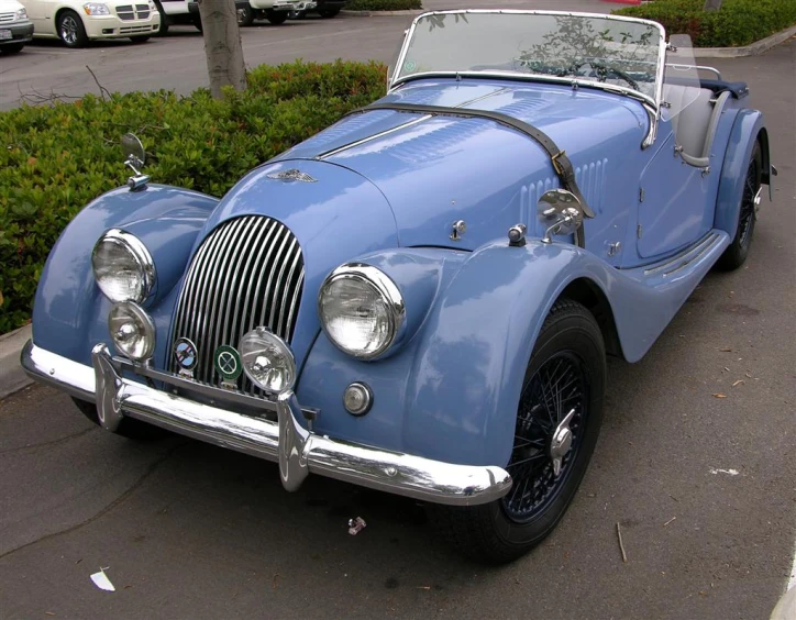 blue vintage car on street in city next to shrubbery