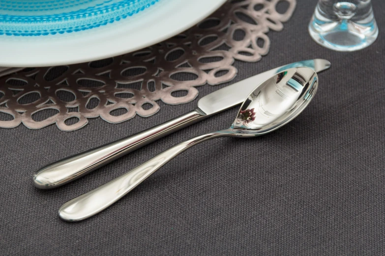 silverware is sitting on a table near a glass of water