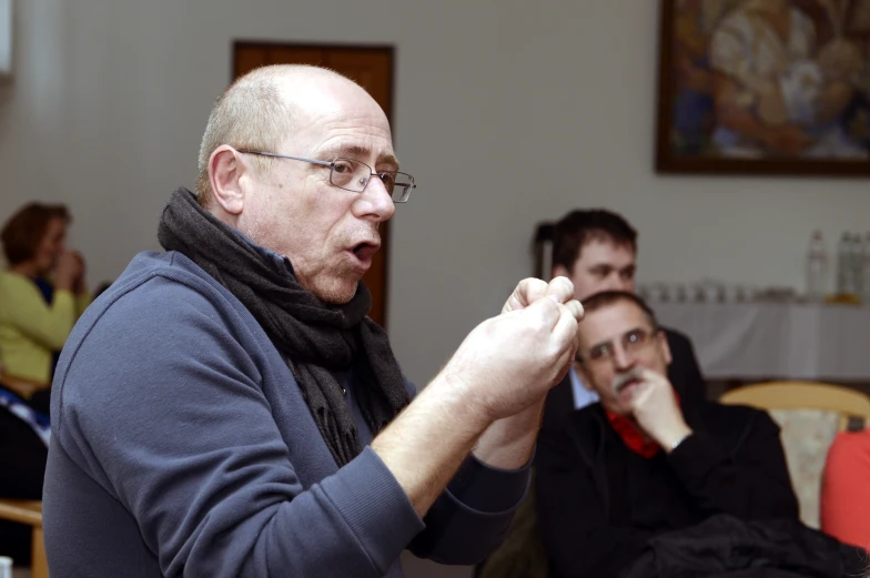 a man standing with his hands clasped in front of two people