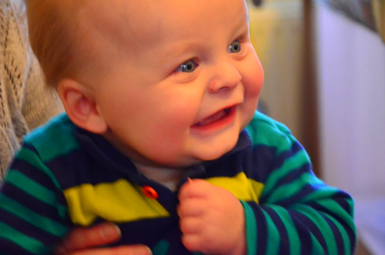 a baby smiles while holding another baby