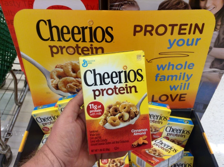 a person holding up cheerios and other cereal