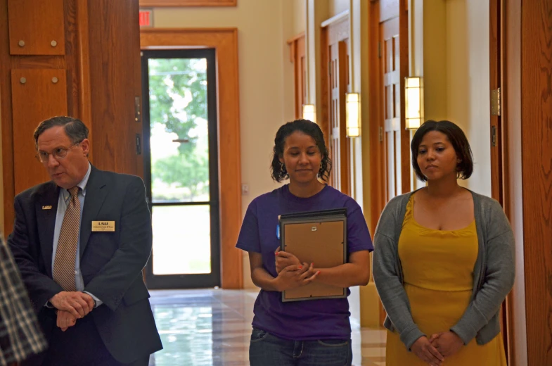 three people standing in a hall looking at soing