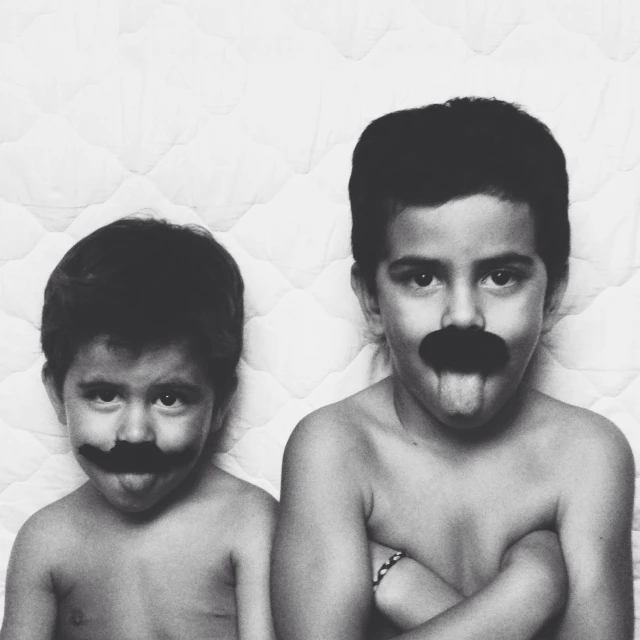 two boys in  poses with fake mustaches on their faces