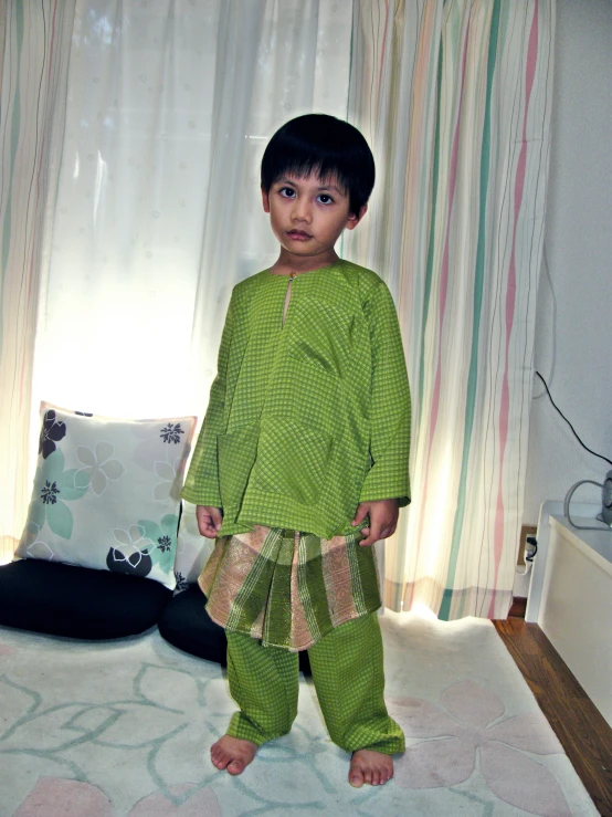a child standing on the floor in green clothes