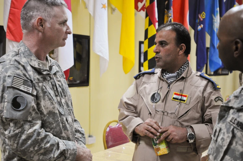 two men in uniforms standing talking in a room