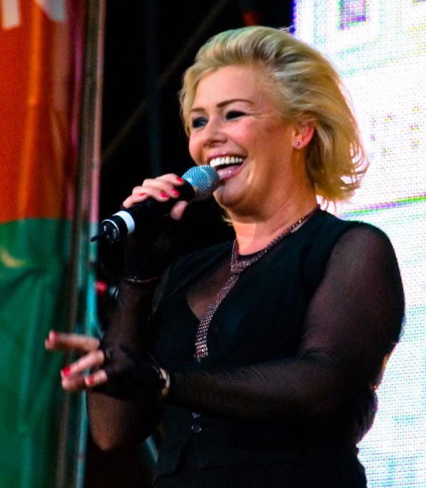woman singing on stage with a microphone in hand