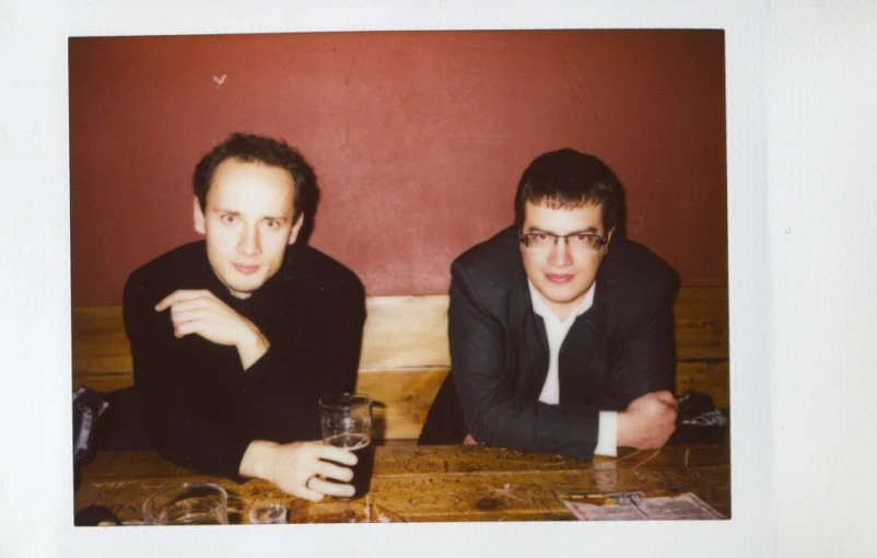 two men sitting at a table next to each other