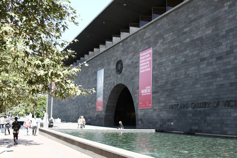 there is people walking near the water fountain in front of the building