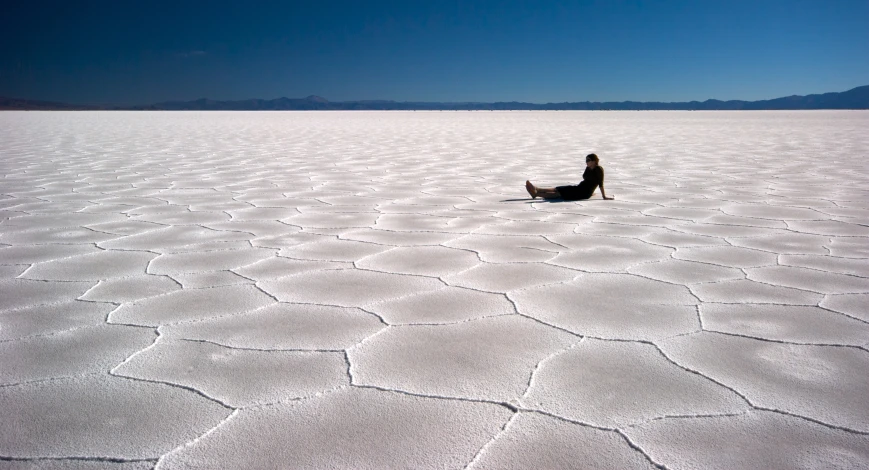 a man is sitting on the ground in the middle of a barren area