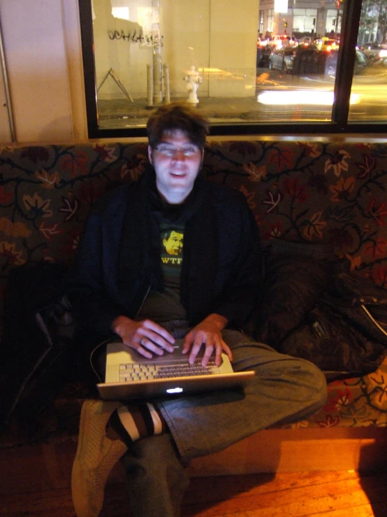 man using laptop on small white table in large room