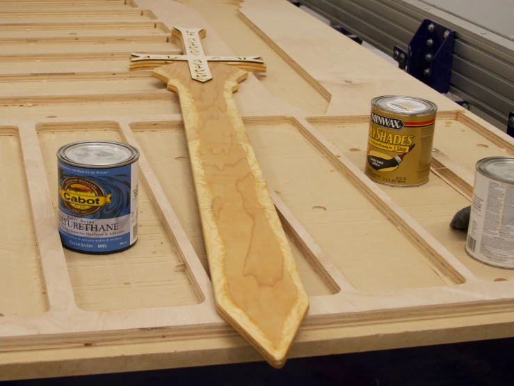 tools, paint, and a woodworking spoon are laying on top of a table