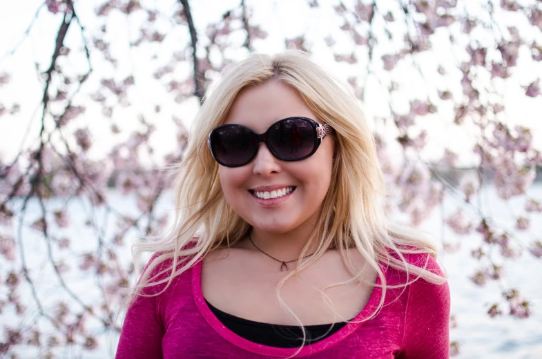 a woman wearing sunglasses and smiling at the camera