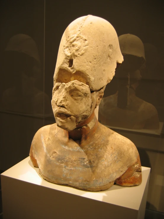 a stone sculpture with a white head, sitting on a stand