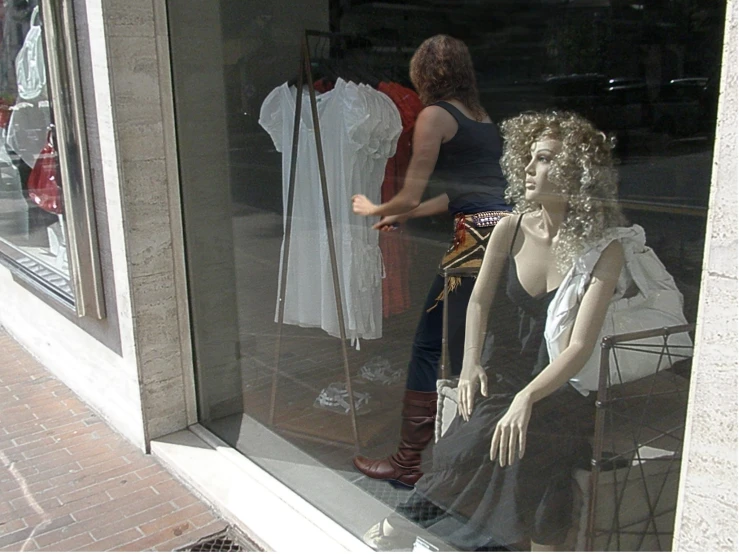 two women look at dresses displayed in a window