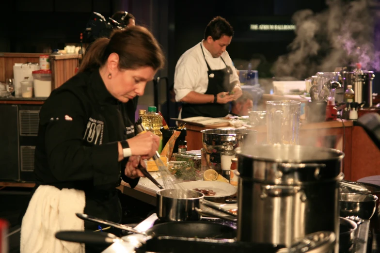 two people standing in a kitchen with pots and pans