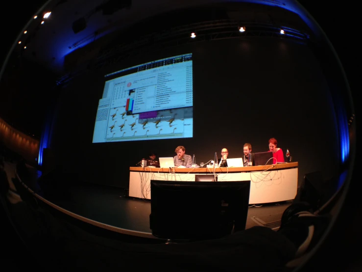 three people are sitting at a conference table