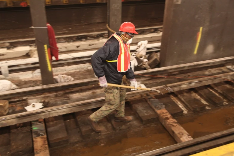 a man in an orange and red safety helmet is standing next to a rail road