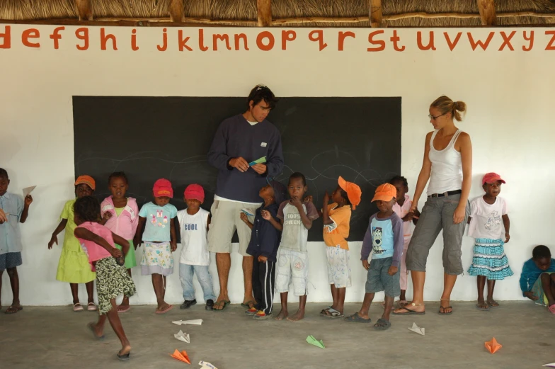 several children and one man stand by a blackboard