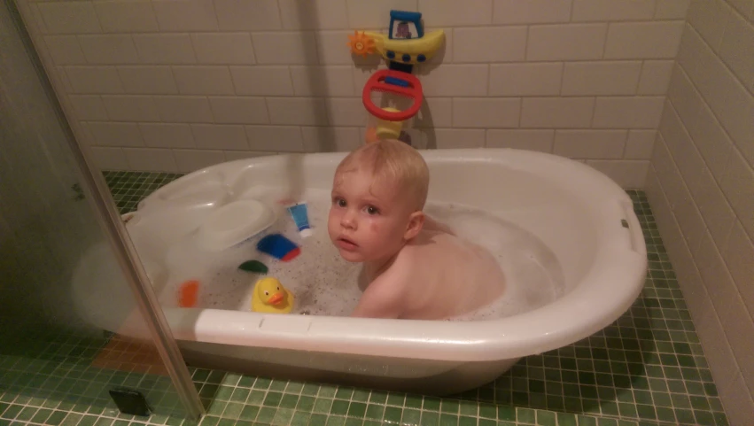 a toddler playing in the tub filled with toys