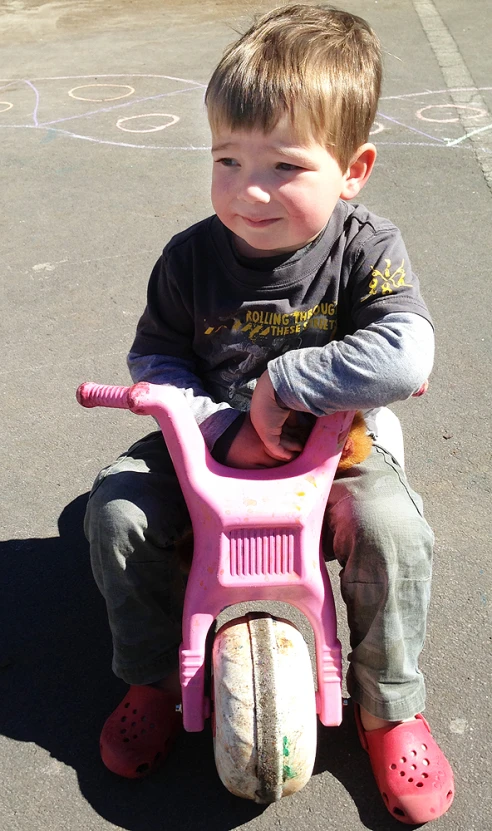 a  riding on a pink little tricycle