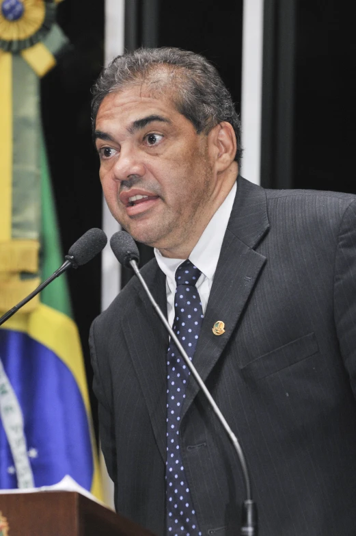 a man in a suit is at a podium and looks to his left