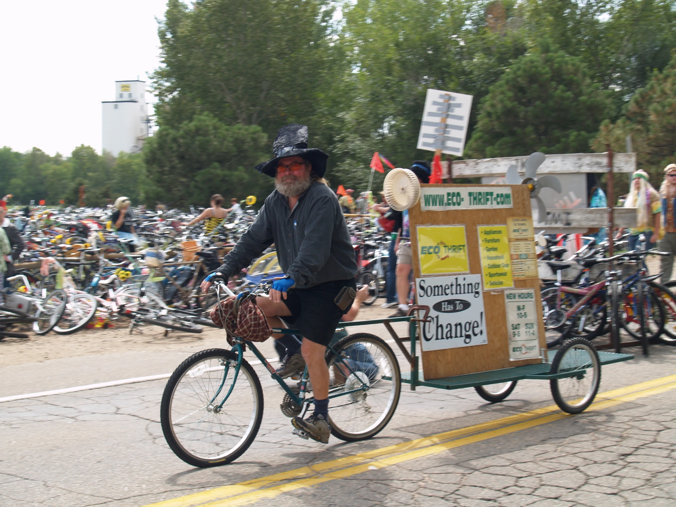 a man riding a bike while wearing a hat and carrying a box