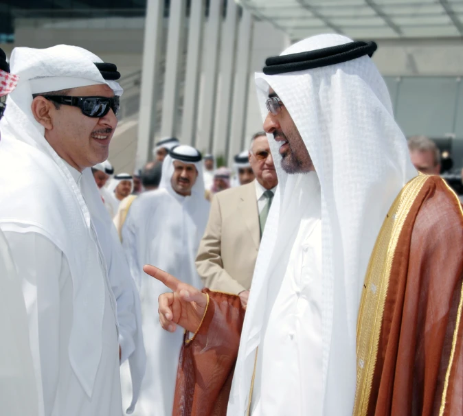 two men talking and standing next to each other