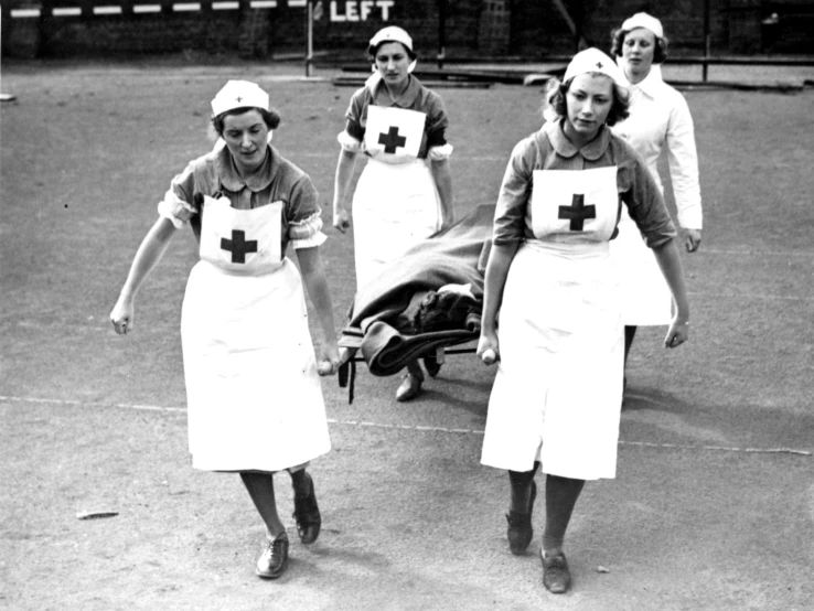 black and white po of women with aprons walking across the tennis court