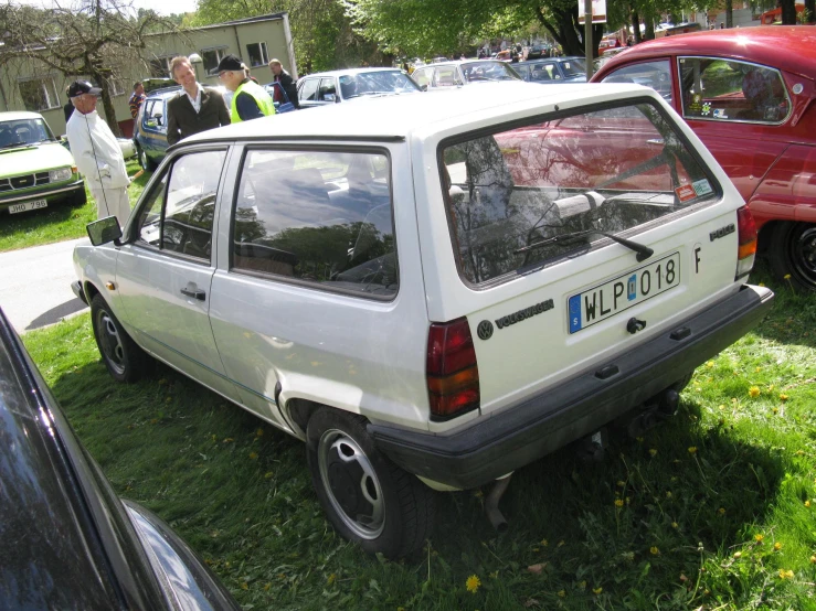 some cars are parked on grass and one is missing the hood